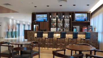Zona de bar moderna con mostradores de mármol, diversas opciones de asientos y una variedad de botellas de licor.