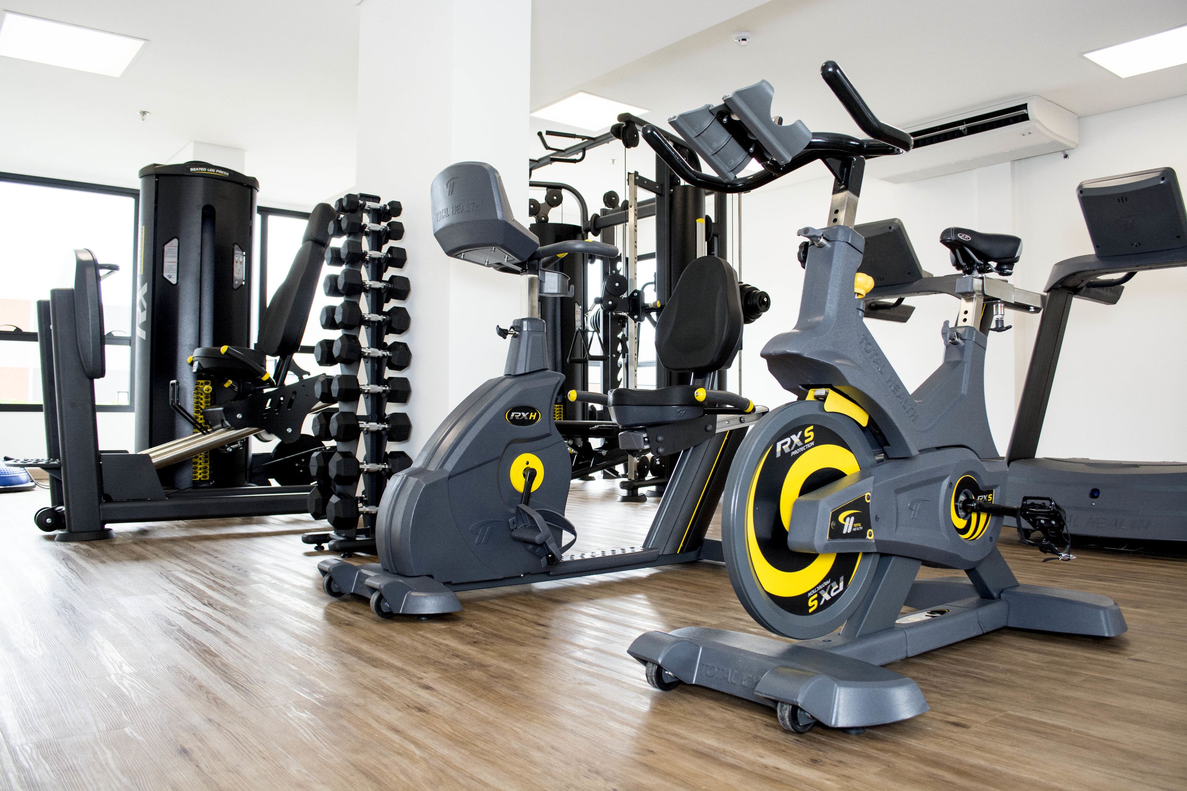 A gym with cardio machines, weightlifting equipment, and a mirror.