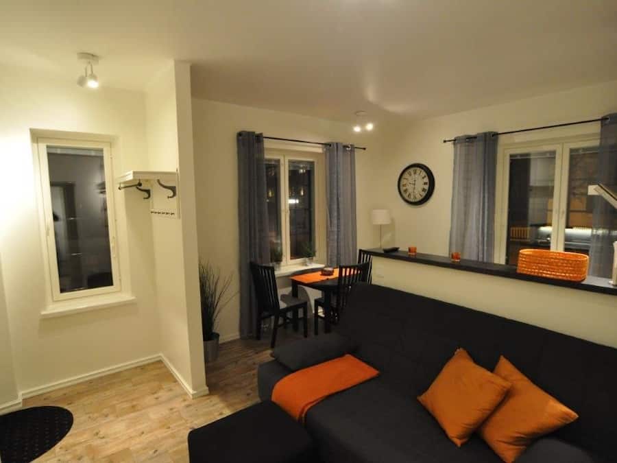 A living room with a sofa, a dining table, and a kitchen area with a window.