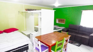 Une pièce comprenant un lit, un bureau avec une chaise, un canapé et un mur vert.