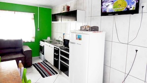 Une cuisine compacte avec des meubles blancs, un four à micro-ondes encastré et un téléviseur fixé au mur.