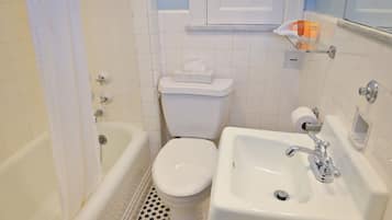 Un baño con inodoro, lavamanos, bañera y toallero.