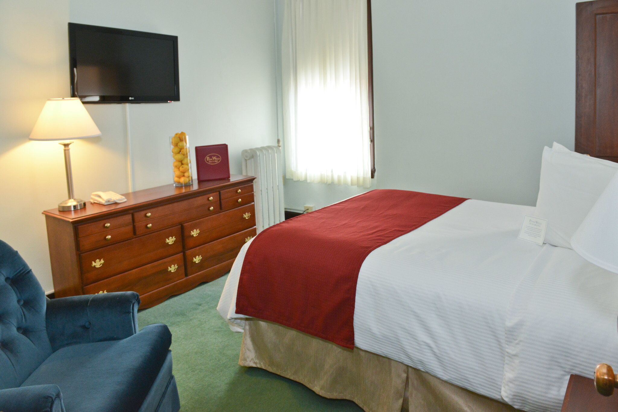 A hotel room with a bed, a dresser, a television, and a chair.