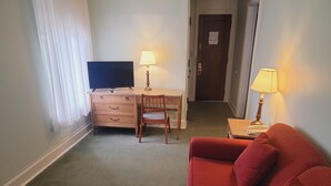 Een hotelkamer met een houten bureau, een televisie, een rode bank en twee lampen.