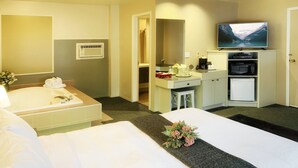 Habitación de hotel con cama, escritorio, televisor de pantalla plana, microondas y refrigerador pequeño.