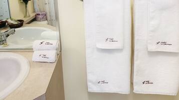 Une salle de bain avec un lavabo, deux serviettes suspendues à un porte-serviettes et un vase de fleurs posé sur le comptoir.