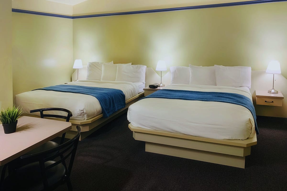 Habitación de hotel con dos camas, un escritorio y una silla.
