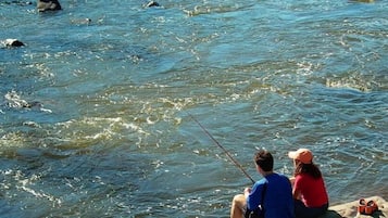 Two people fishing by a river.