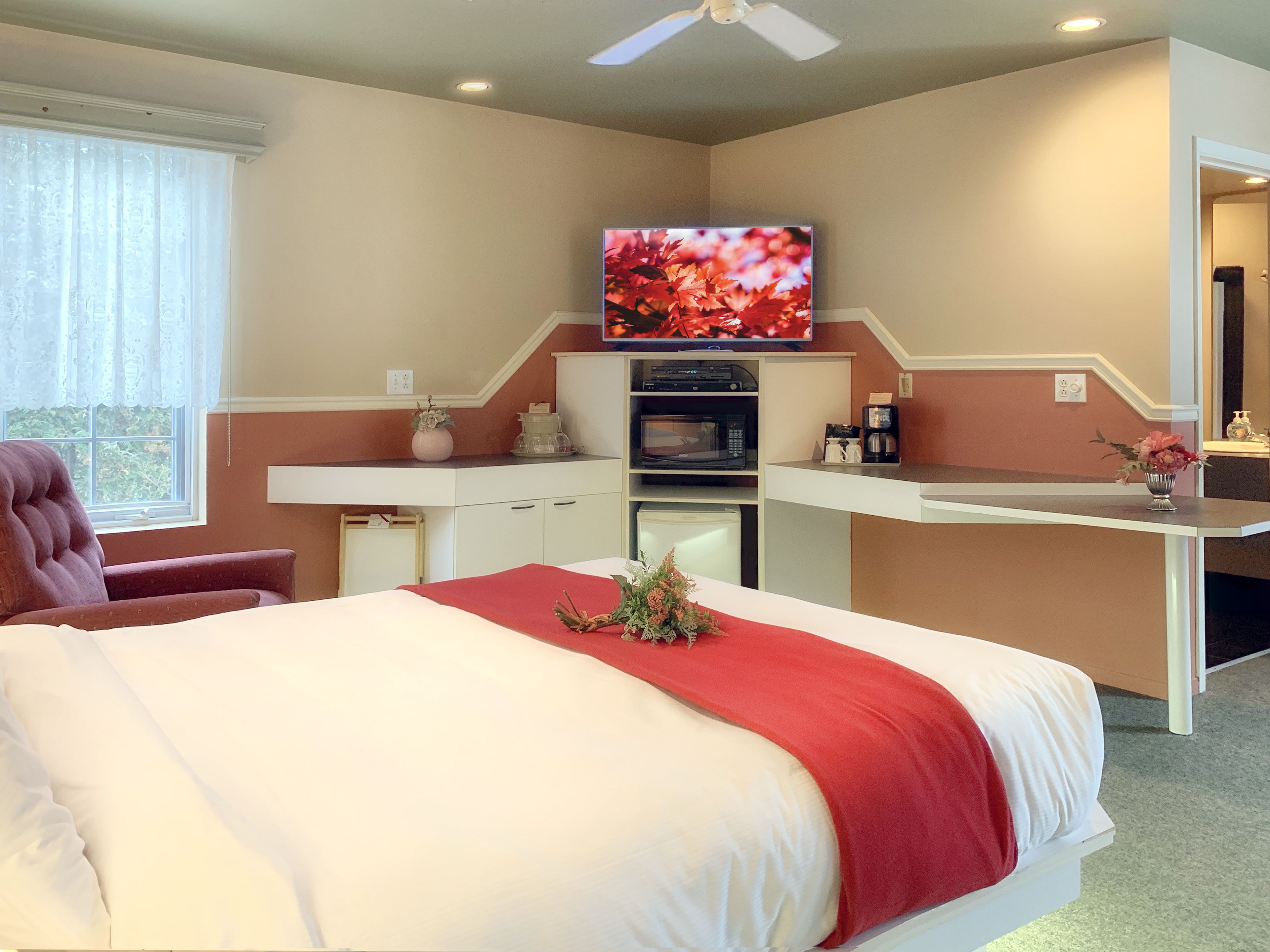 Una habitación de hotel con cama, escritorio, televisión, microondas y cafetera.
