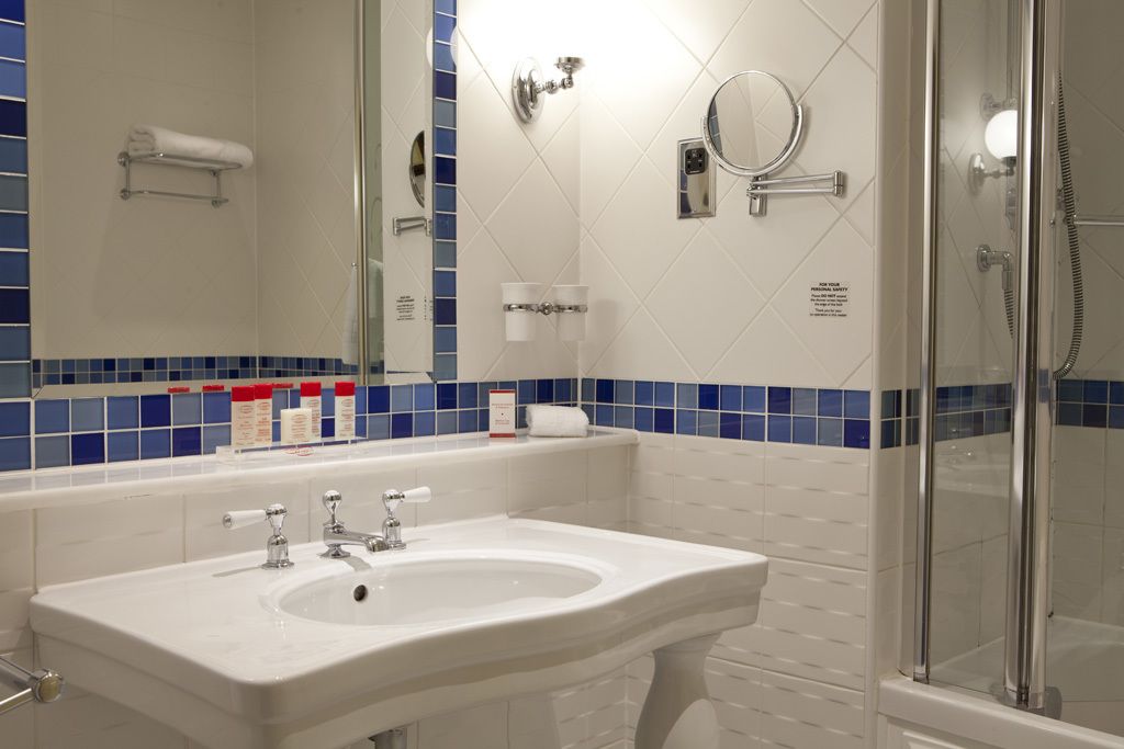 Ein Badezimmer mit einem weißen Waschbecken, einem Spiegel und einer Duschkabine aus Glas.