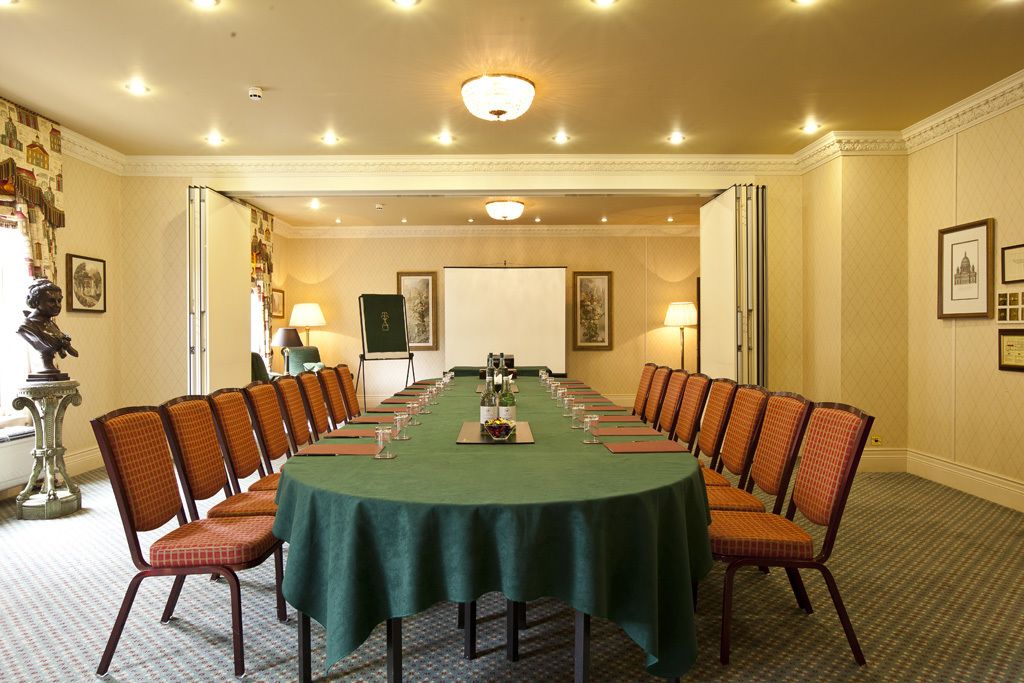 A conference room with a long table, chairs, and a projector screen.
