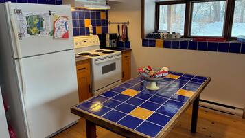 Una cocina con refrigerador, estufa, horno y una mesa con un diseño de azulejos azules y amarillos.