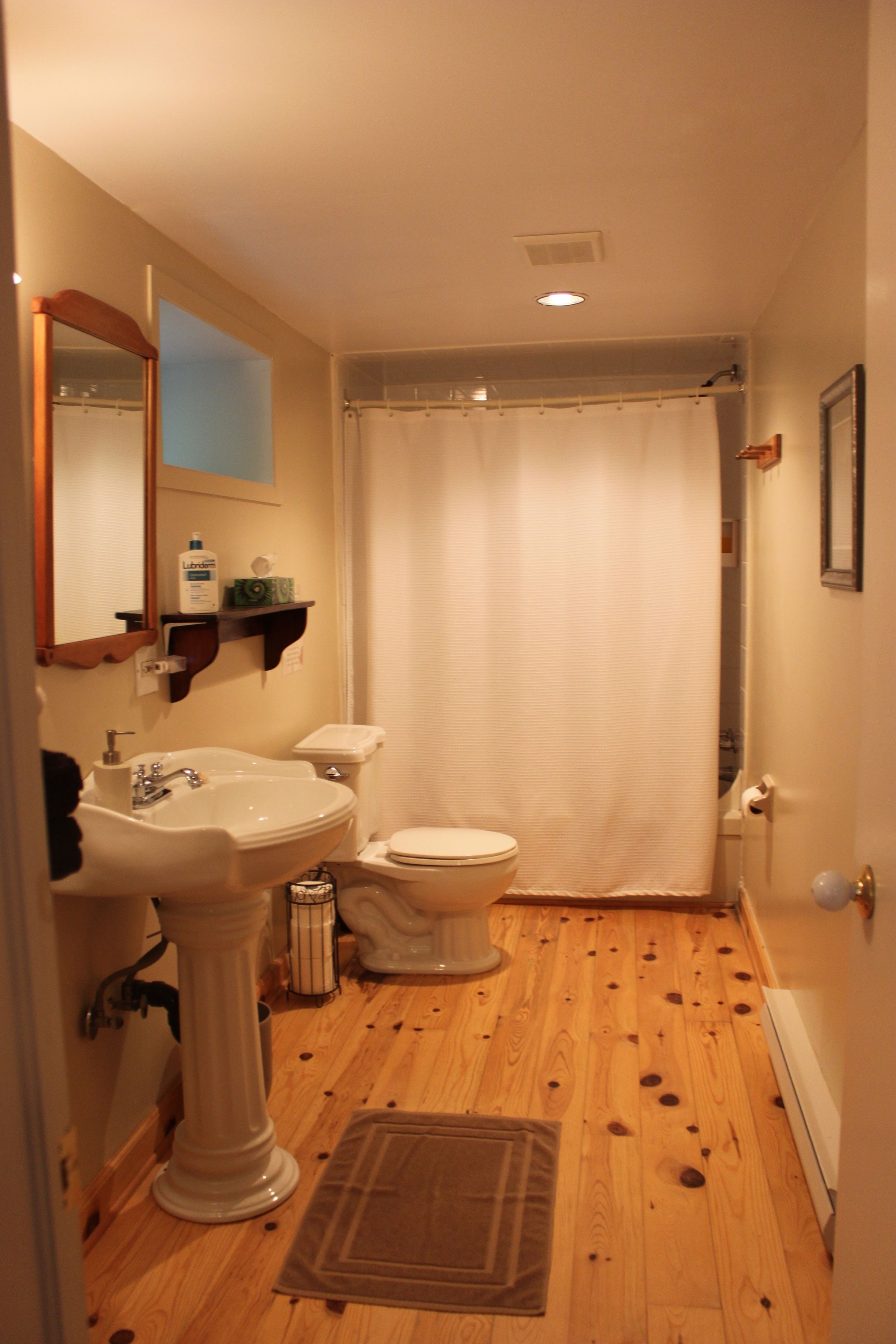 A bathroom with a pedestal sink, toilet, and shower curtain.