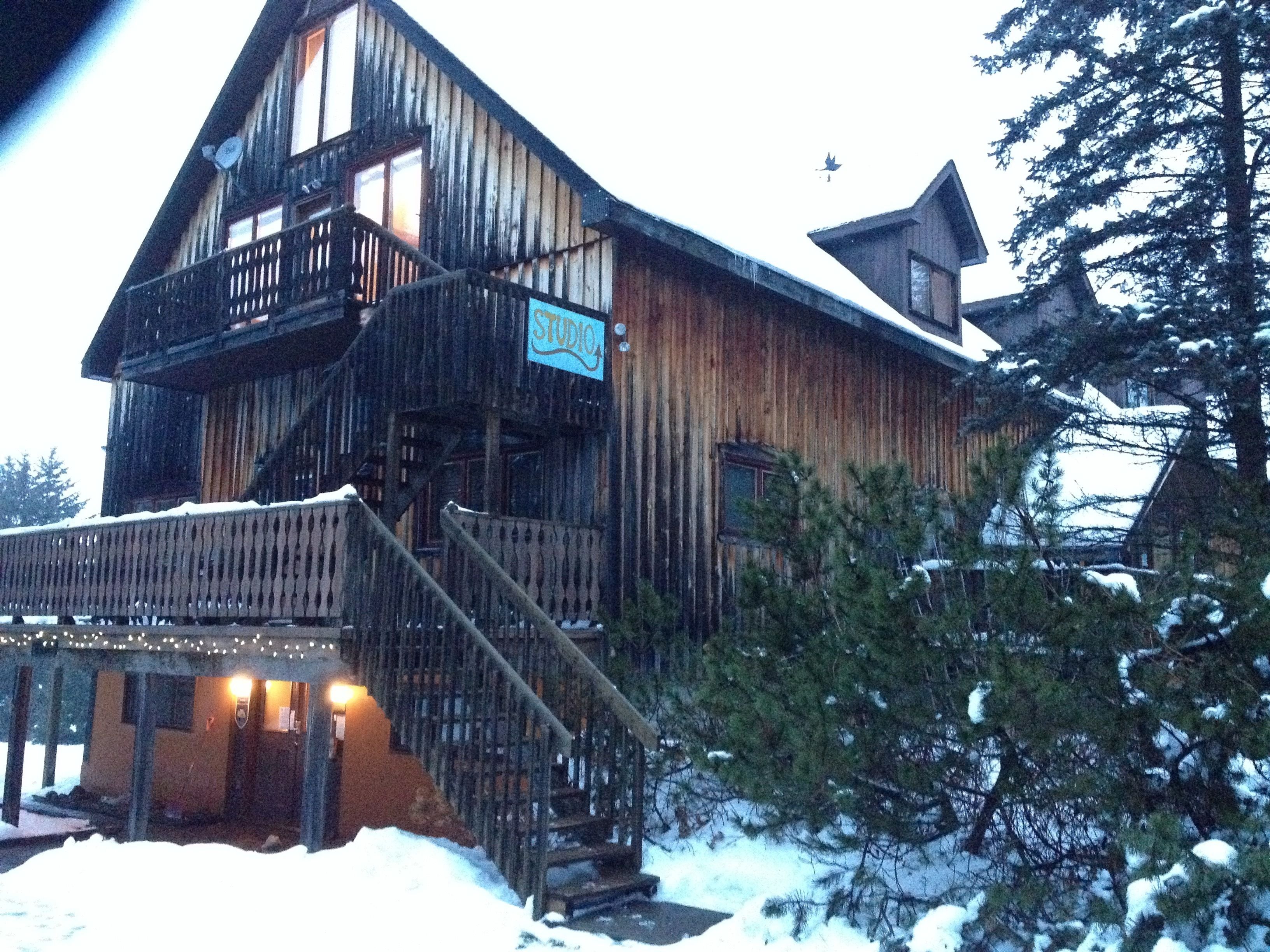 A wooden cabin with a balcony and a sign that reads "STUDIO".