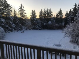 Une terrasse enneigée avec un banc et une vue sur un paysage hivernal, avec des arbres couverts de neige.