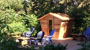 Un pontile in legno con due poltrone Adirondack blu e un piccolo capanno di legno.
