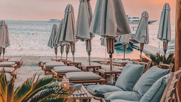 A beachside lounge with wooden chairs and umbrellas, overlooking the sea. - Branco Mykonos (Mykonos)