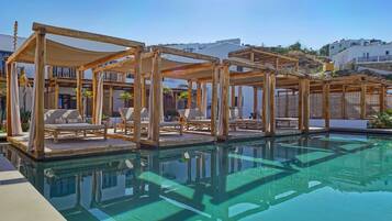 Relax by the serene pool surrounded by shaded lounge chairs and modern buildings in the background.