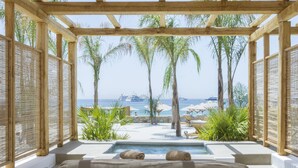 A spa area with a pool, wooden pergola, and lounge chairs. - Branco Mykonos (Mykonos)