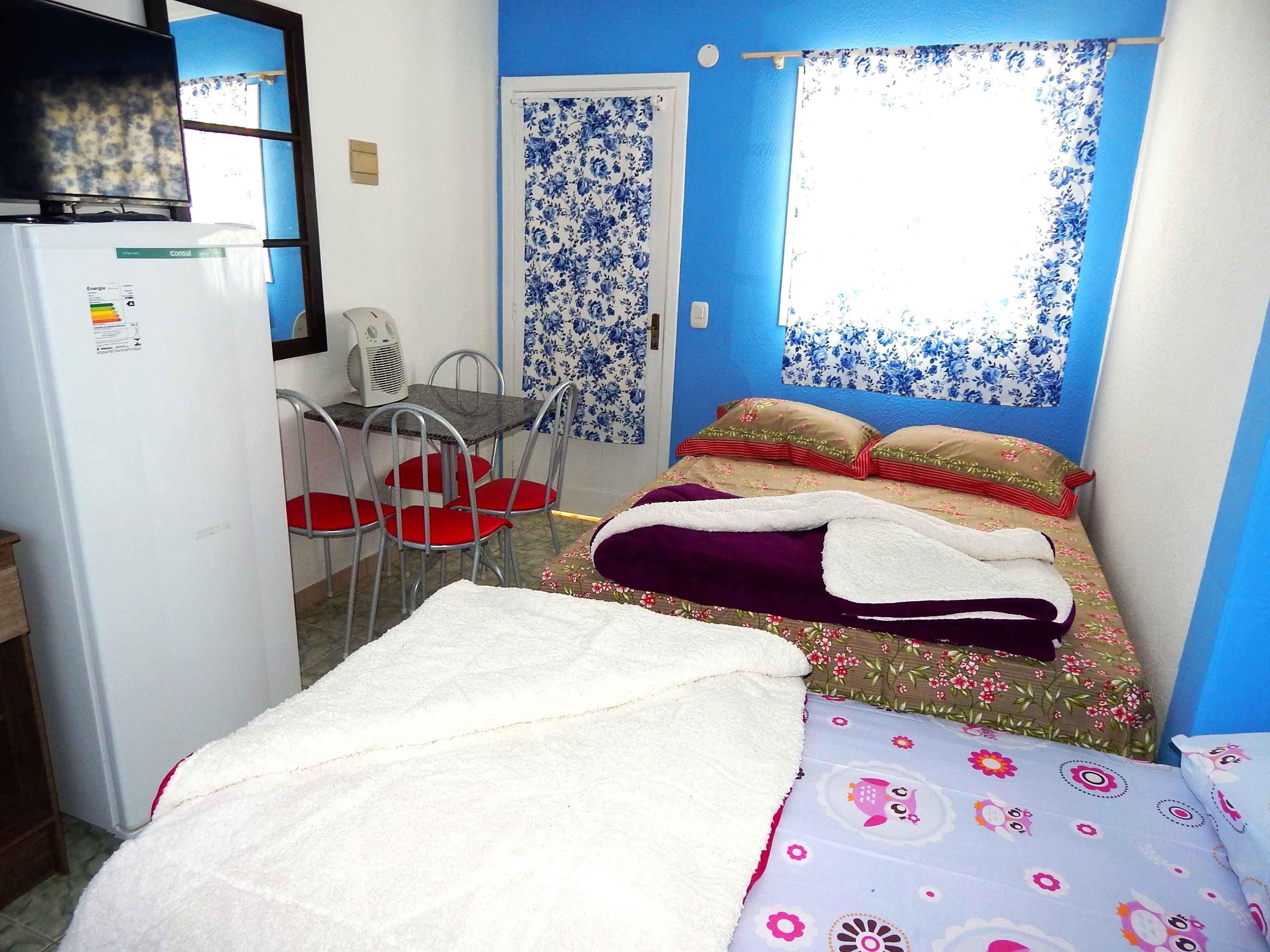 A small, brightly colored room with a bed, a desk, and a chair.