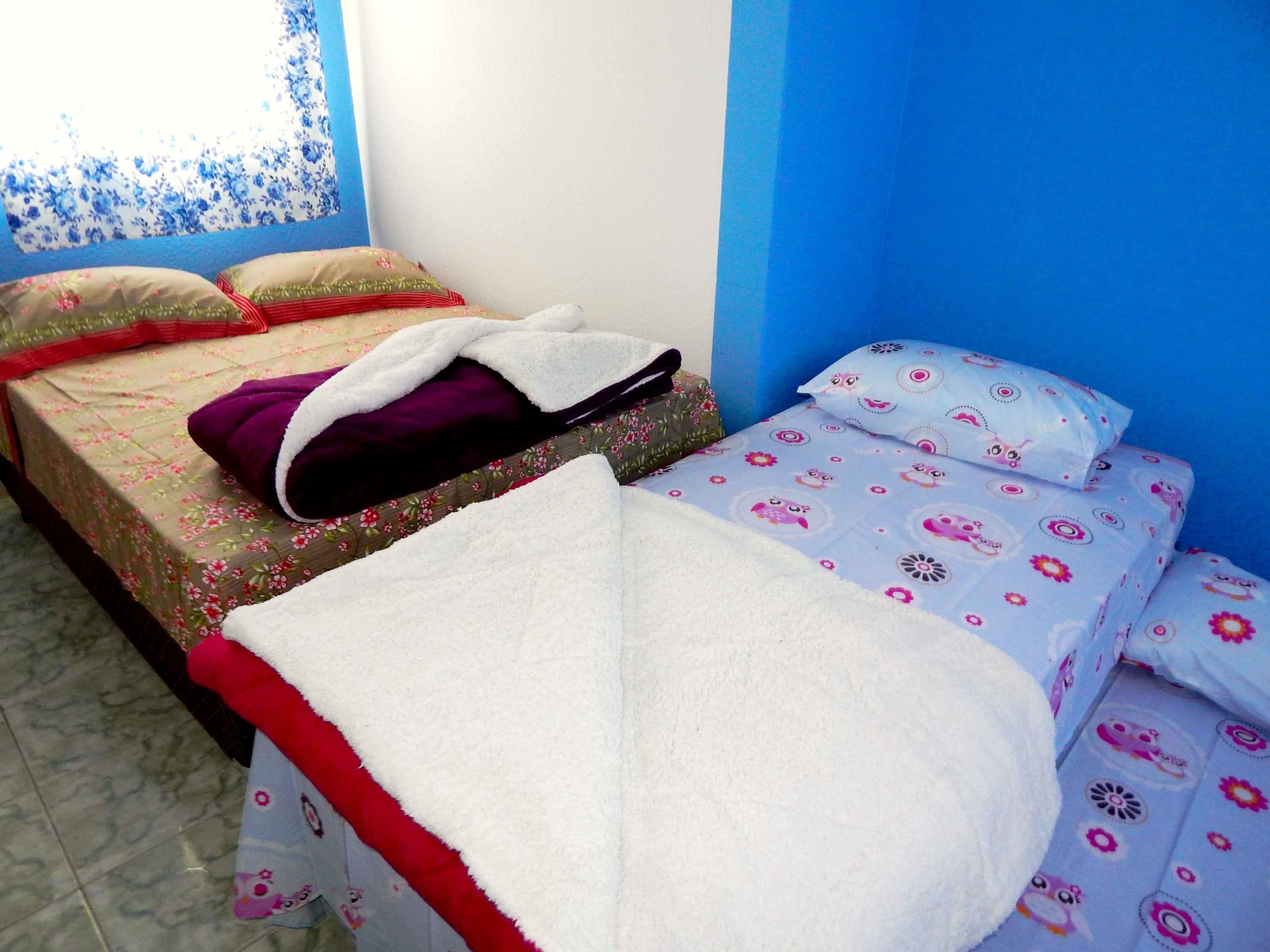 A room with two beds, one with a floral bedspread and the other with a patterned bedspread.