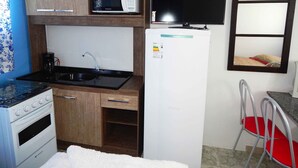 Cocina compacta equipada con microondas, estufa, fregadero y refrigerador.
