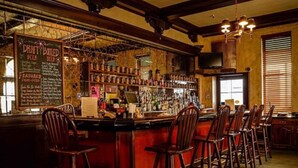 Un bar con mostrador de madera, taburetes y una pizarra con la carta de cervezas de barril.