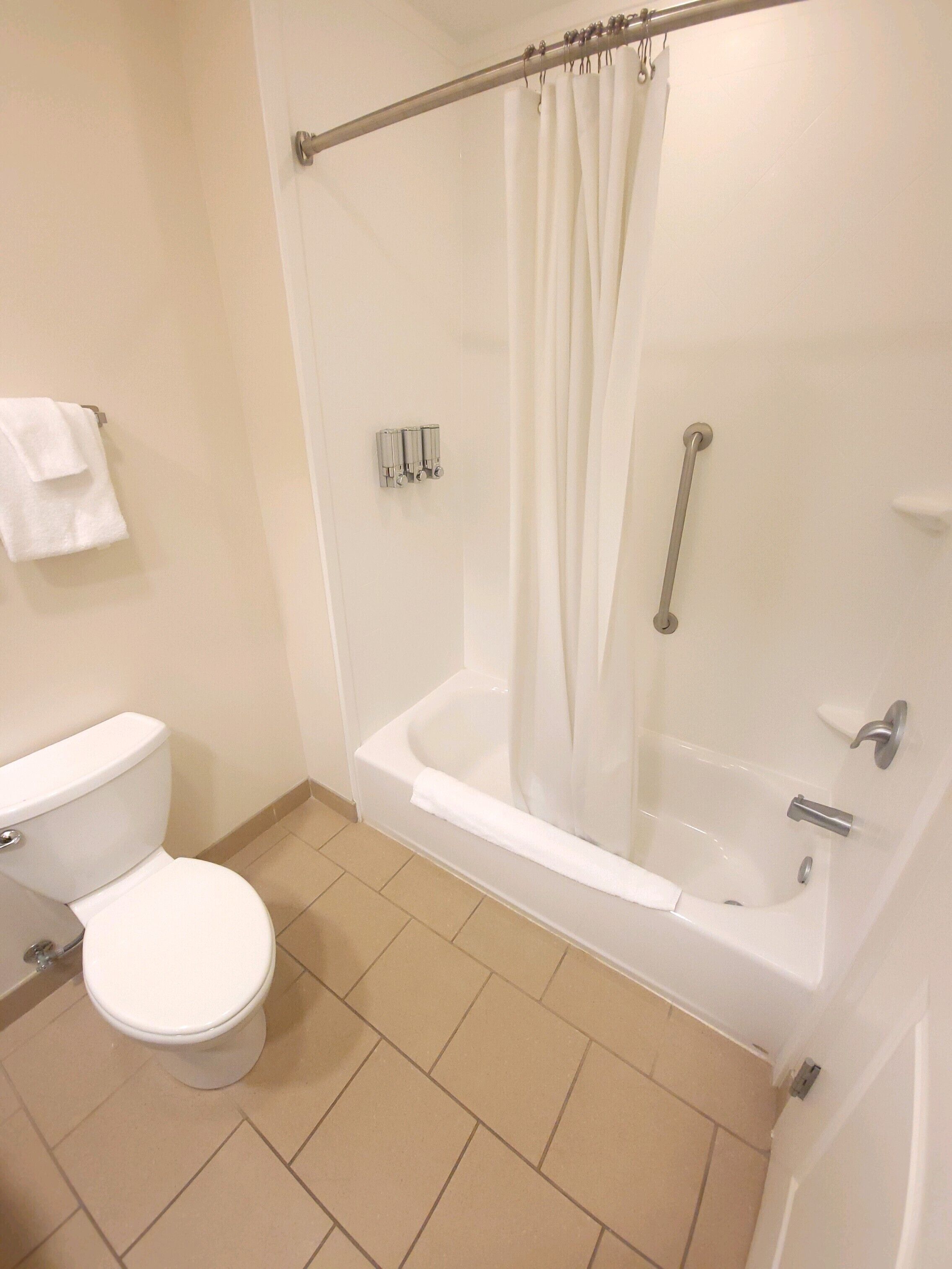 Un bagno con il water, una vasca e una tenda da doccia.