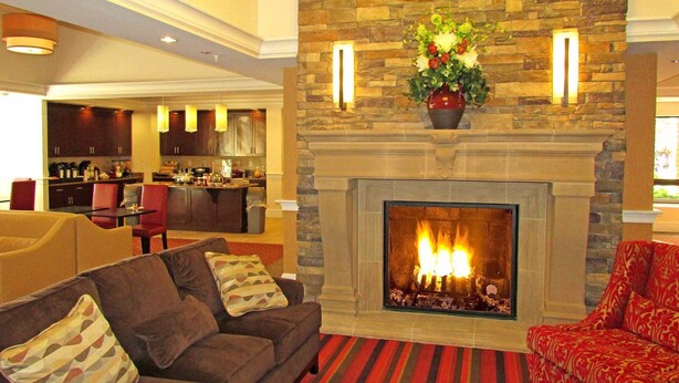 Una sala de estar con chimenea, una cocina al fondo y un comedor.