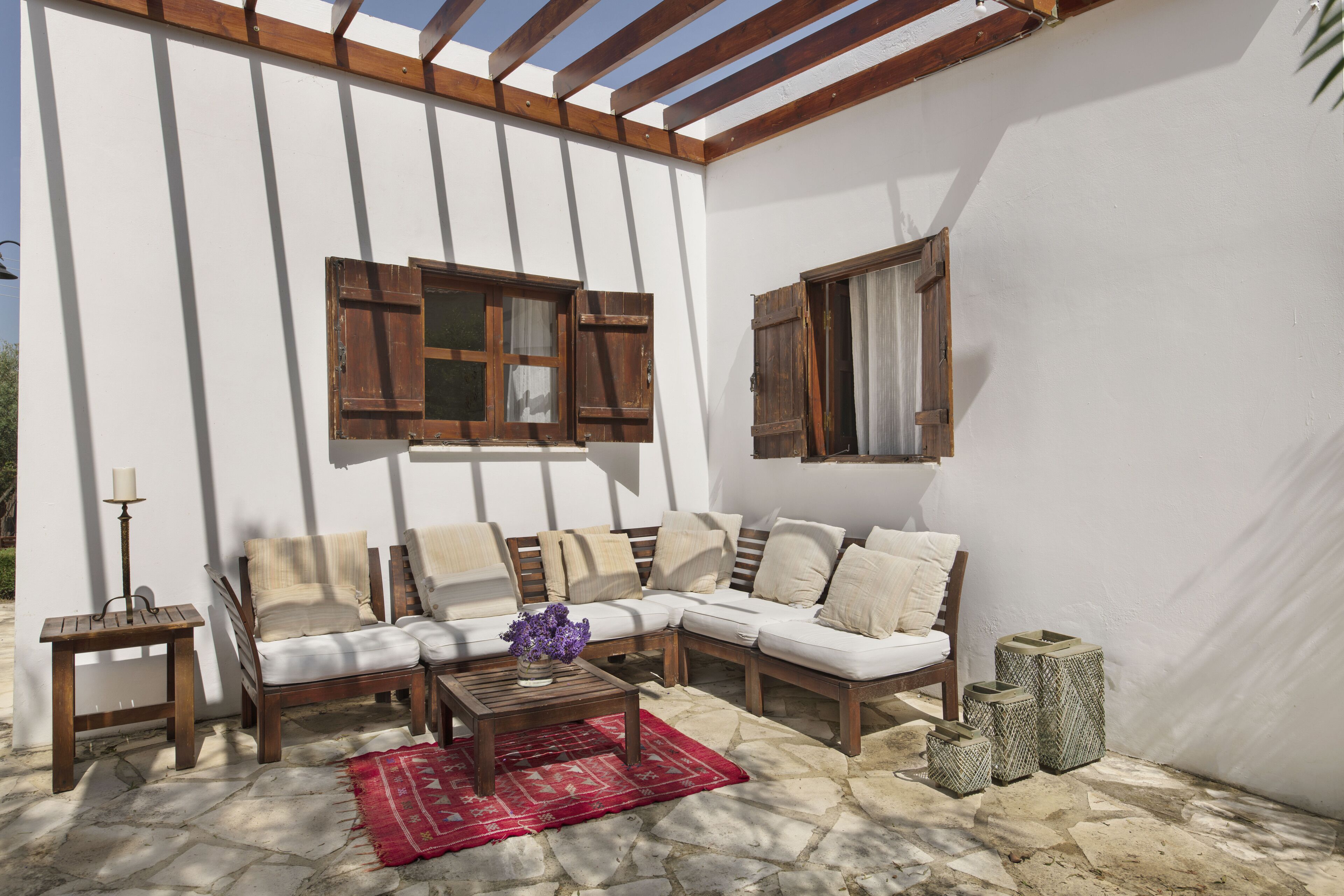 Eine sonnendurchflutete Terrasse mit einer Holzbank, einem Sofa und einem Couchtisch.