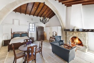 Una habitación amplia con una cama grande, chimenea, zona de comedor y sala de estar con un sofá azul.