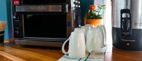 A kitchen with a Waring coffee maker, a Waring toaster oven, and a Hamilton Beach slow cooker on the counter.