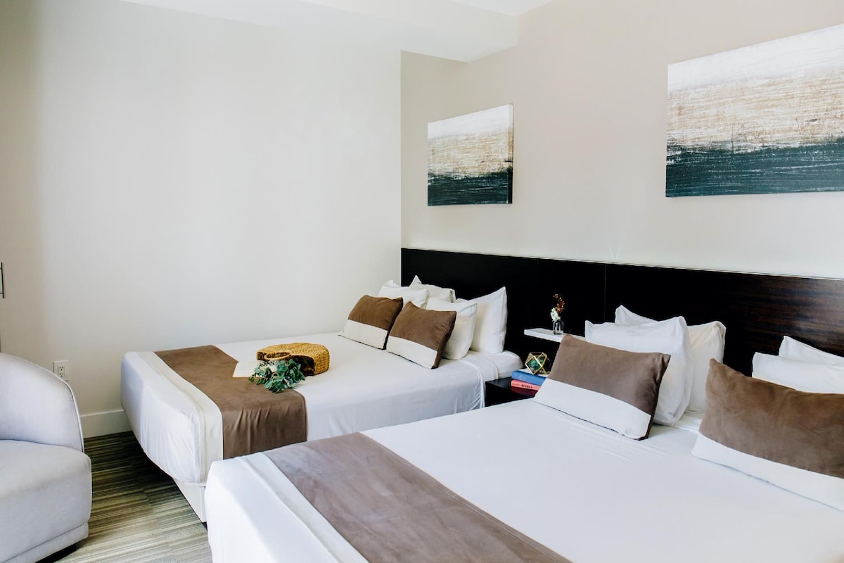 Een hotelkamer met twee bedden, een bank en kunstwerken aan de muur.