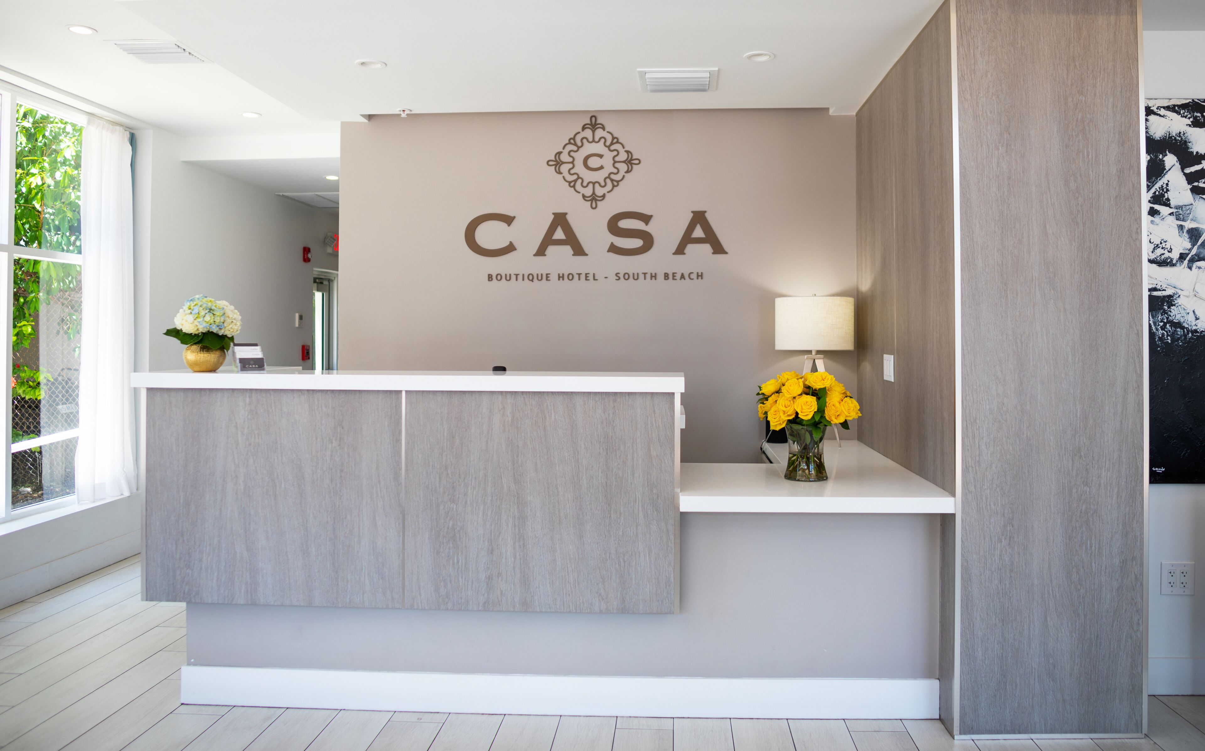 Una mesa de recepción con el logotipo y el nombre "CASA Boutique Hotel - South Beach".