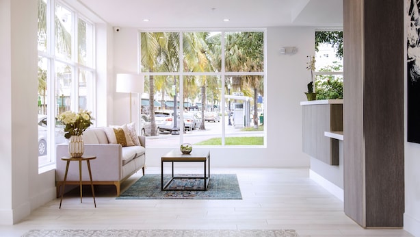 A modern living room with a sofa, a coffee table, and a vase of flowers. - Casa Boutique Hotel (Miami Beach)