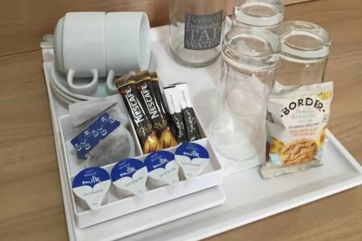A tray with a water bottle, coffee maker, coffee pods, and a bag of coffee.