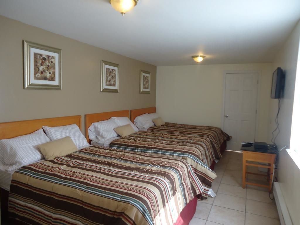 A hotel room with two beds, a desk, and a television.