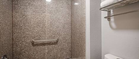 A bathroom with a shower, a bathtub, and a towel rack.