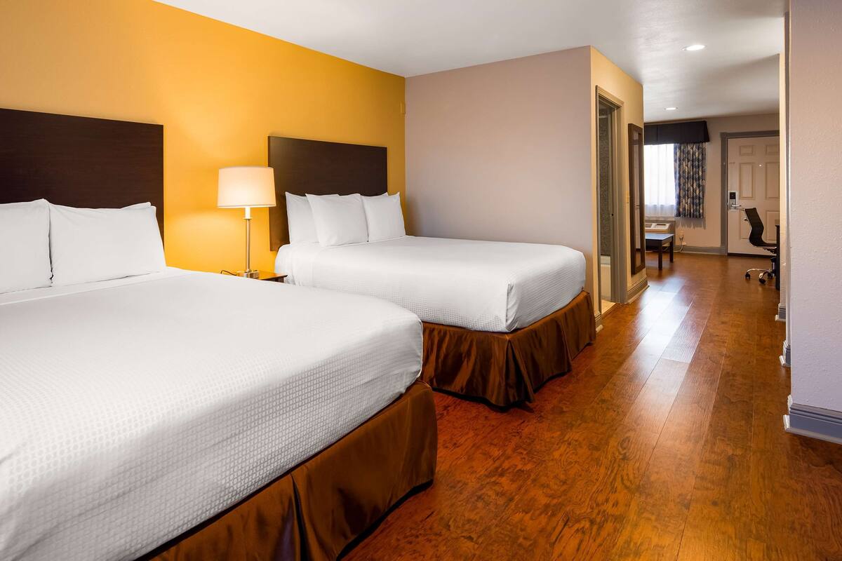 Une chambre d’hôtel avec deux lits, un bureau et une chaise.