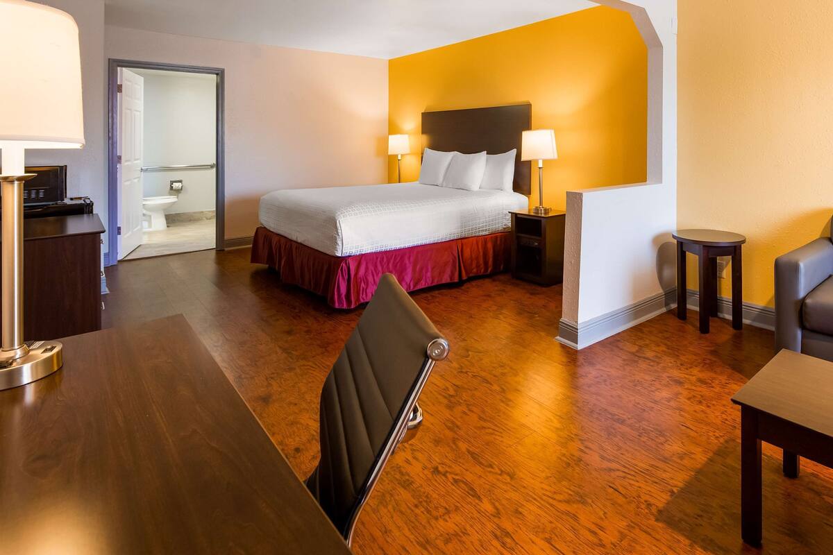 Une chambre d’hôtel comprenant un lit, des tables de chevet, un bureau, une chaise et un canapé.