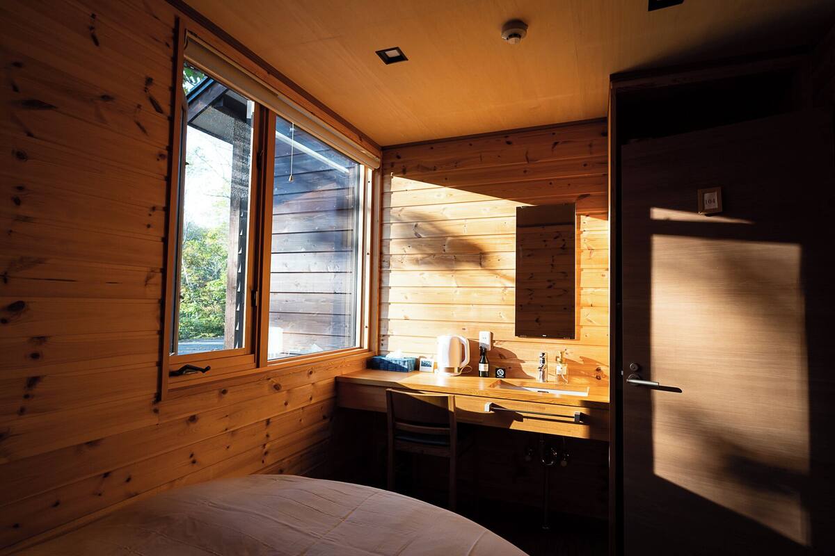 A cabin with a wooden interior, a large window, a sink, and a refrigerator.