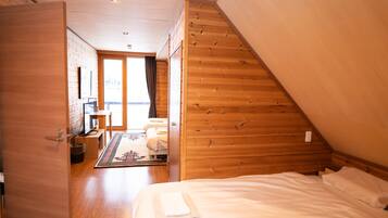 Una camera da letto con soffitto in legno spiovente, un letto, una scrivania e una sedia.