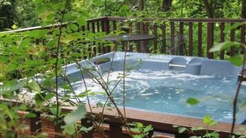 Un bain à remous entouré d’une terrasse en bois et d’une végétation luxuriante.