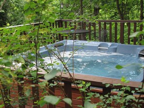 A hot tub surrounded by a wooden deck and lush greenery. - 5 Ojo Inn Bed and Breakfast (Eureka Springs)