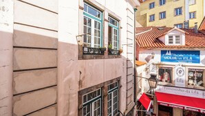 Una calle estrecha con edificios, una tienda con toldo rojo y un cartel que dice 'Terreirinho da Lila'.