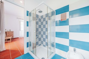A shower with a glass door, a sink, and a tiled floor. - Casas da Biquinha (Sintra)