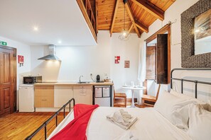 A compact room with a bed, a small kitchenette, a dining table, and a wooden ceiling. - Casas da Biquinha (Sintra)