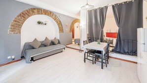 Un espacio habitable moderno con sofá, mesa de comedor y un arco de ladrillo.