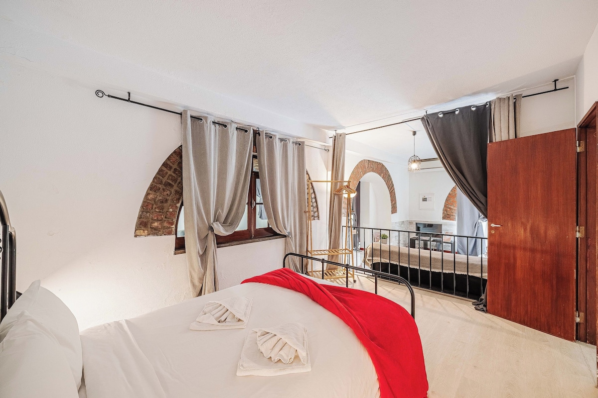 A bedroom with a bed, curtains, a wooden door, and a view of a balcony.