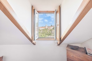 A room with a skylight, a wooden dresser, and a view of buildings and trees. - Casas da Biquinha (Sintra)